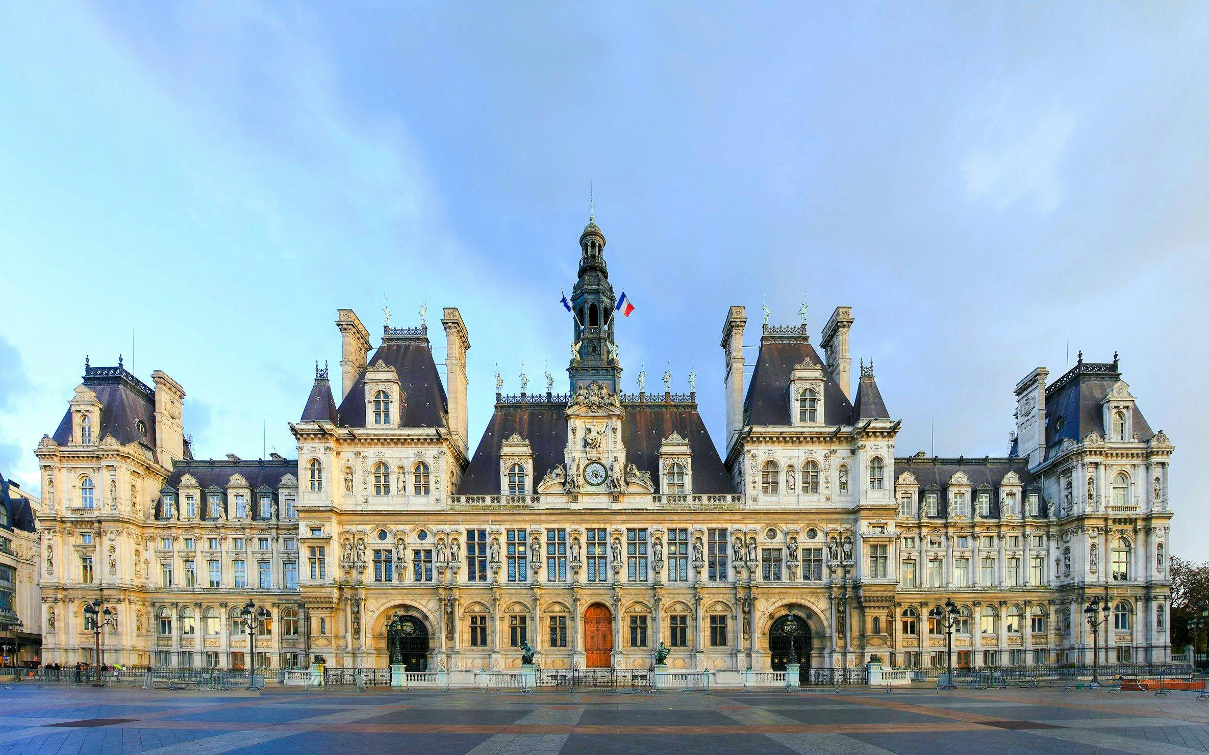 Hôtel de Ville facade in Paris with French flags and ornate architecture.