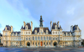 Hôtel de Ville facade in Paris with French flags and ornate architecture.