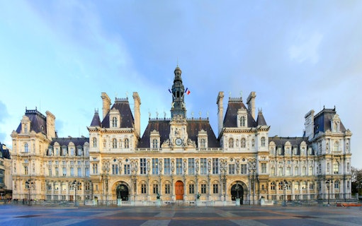 Hôtel de Ville facade in Paris with French flags and ornate architecture.