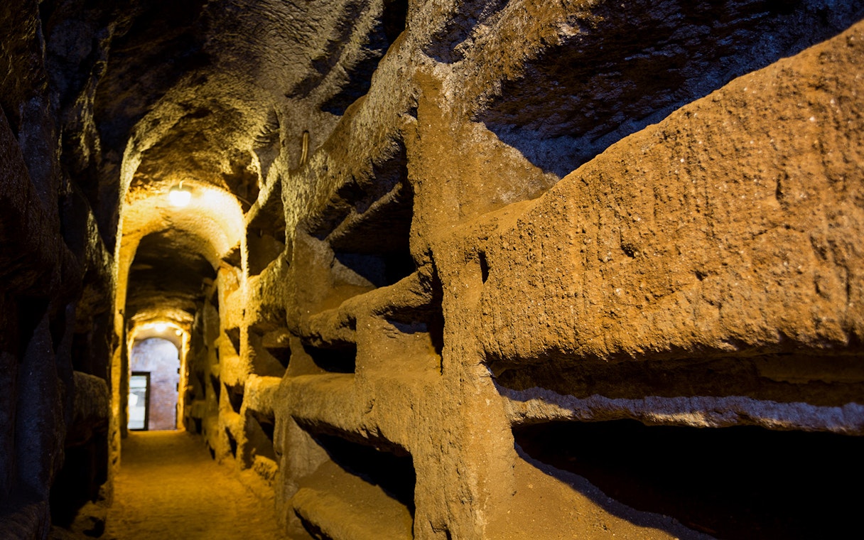 Underground passageway in the Catacombs of Saint Callixtus, Rome, with illuminated niches.