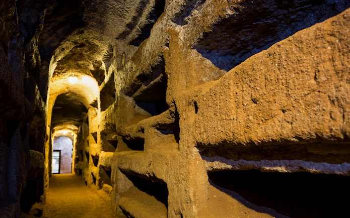 Underground passageway in the Catacombs of Saint Callixtus, Rome, with illuminated niches.