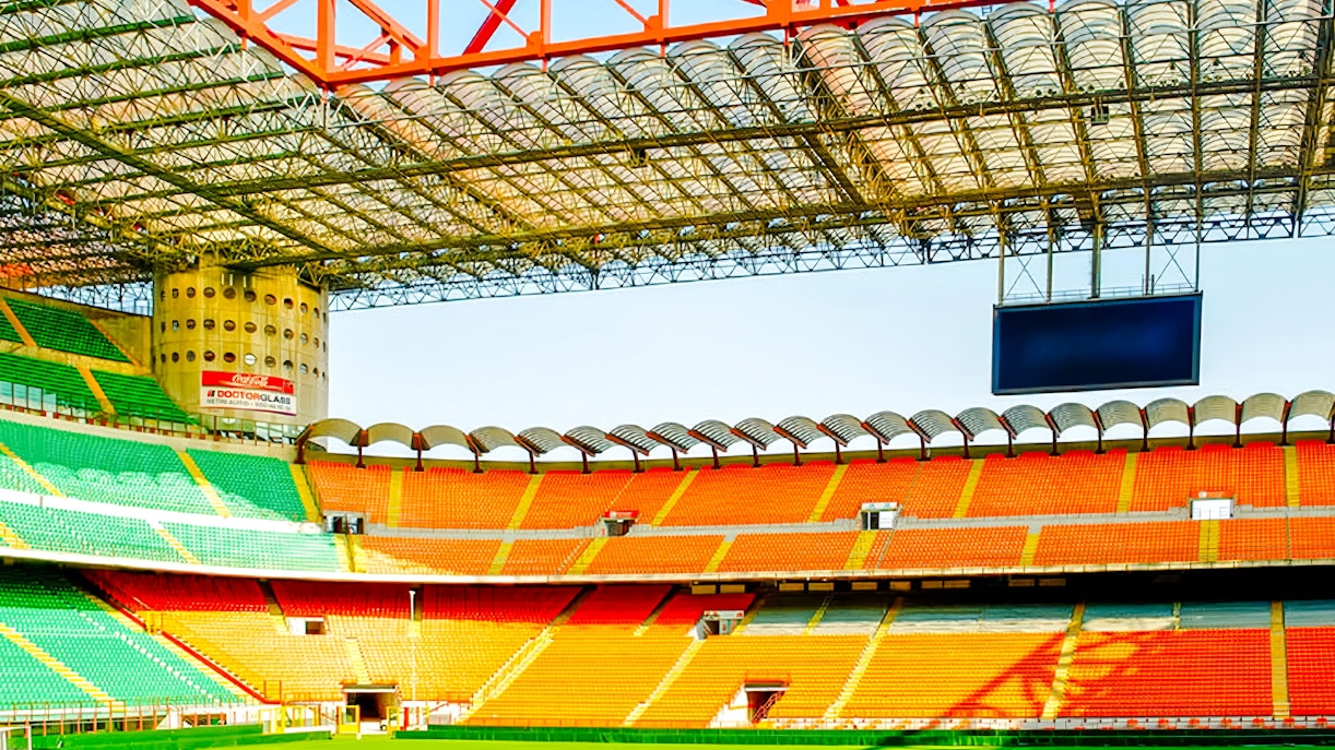 San Siro stadium field with colorful seating and large screen in Milan, Italy.