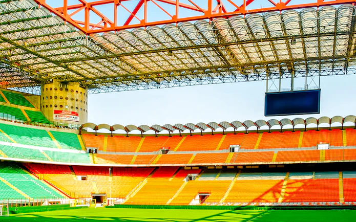 San Siro stadium field with colorful seating and large screen in Milan, Italy.