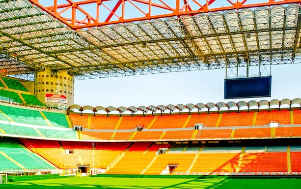 San Siro stadium field with colorful seating and large screen in Milan, Italy.