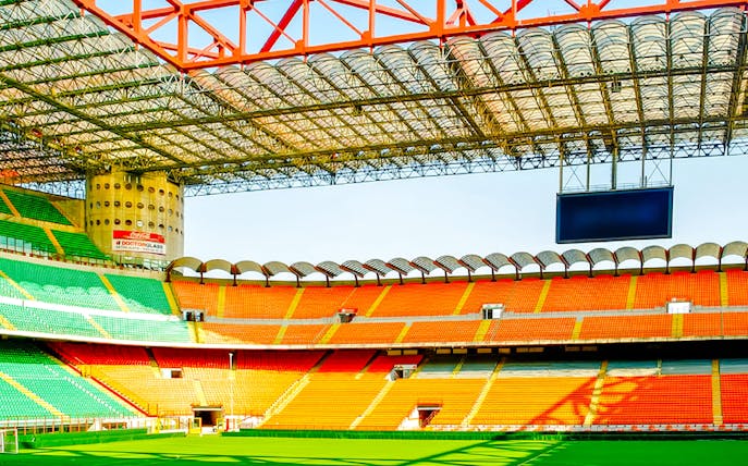 San Siro stadium field with colorful seating and large screen in Milan, Italy.