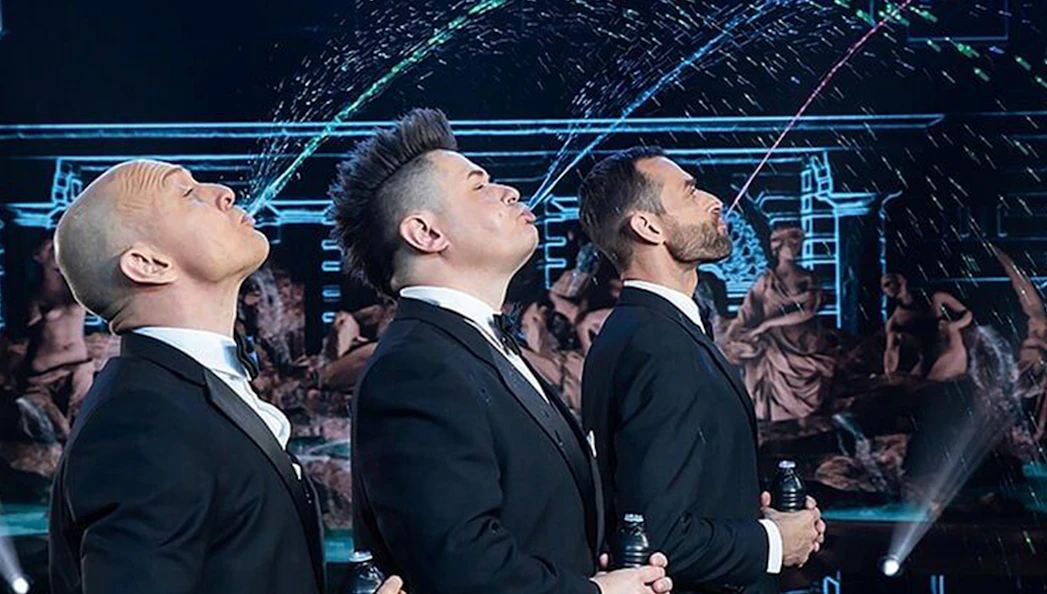 Performers in suits at Big Apple Circus Holiday Show creating water arcs on stage.