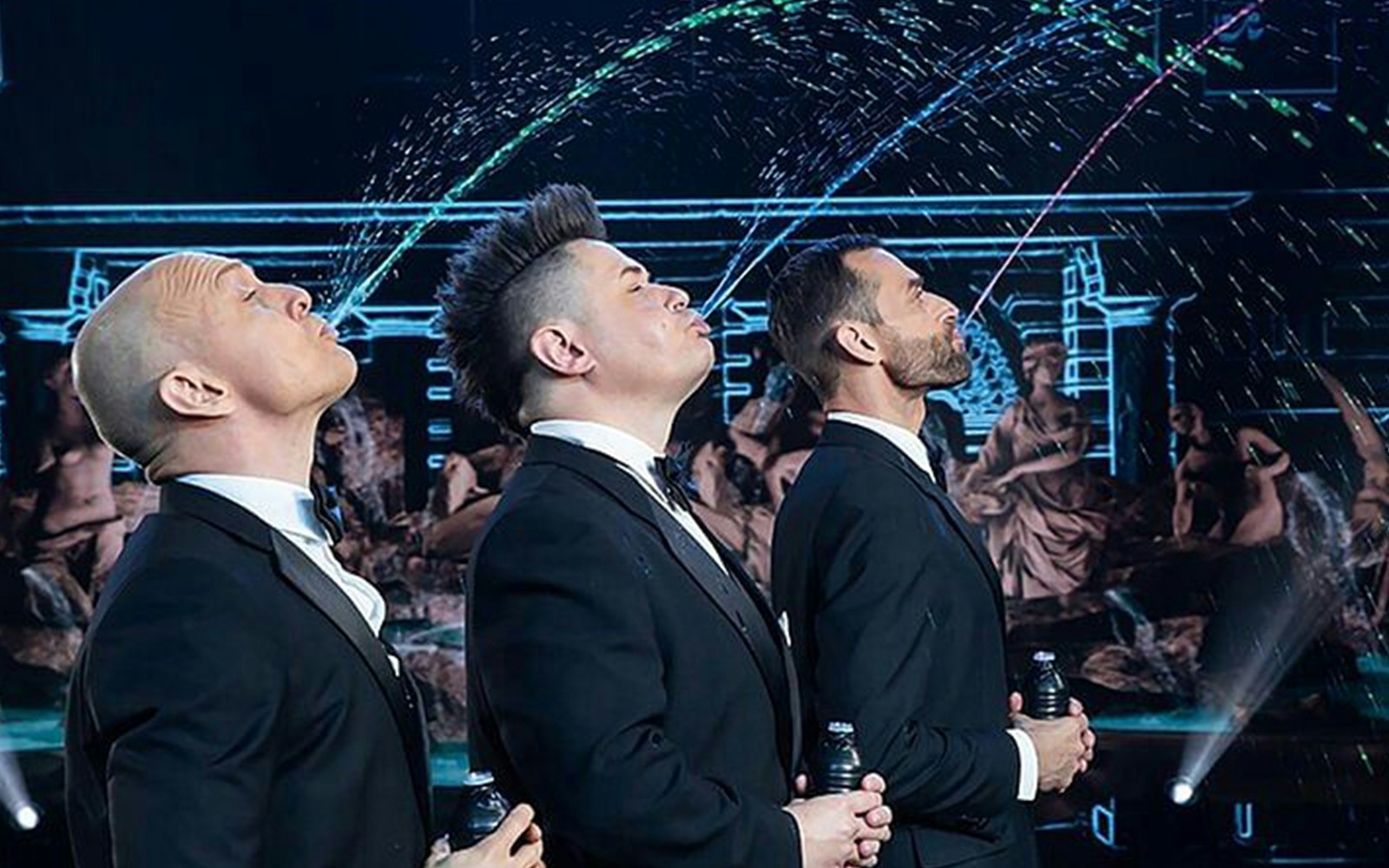 Performers in suits at Big Apple Circus Holiday Show creating water arcs on stage.