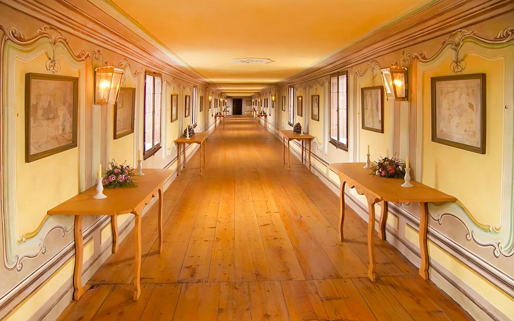 Cesky Krumlov castle corridor with wooden tables and framed art.