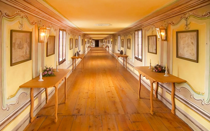 Cesky Krumlov castle corridor with wooden tables and framed art.