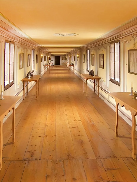 Cesky Krumlov castle corridor with wooden tables and framed art.