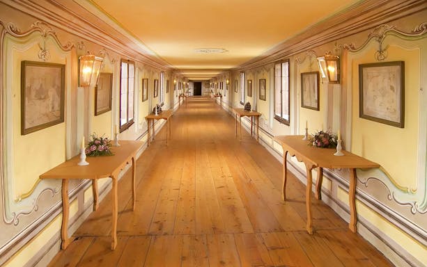 Cesky Krumlov castle corridor with wooden tables and framed art.