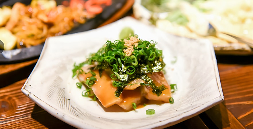 Plate of Japanese dish garnished with green onions and seaweed on Tokyo food tour.
