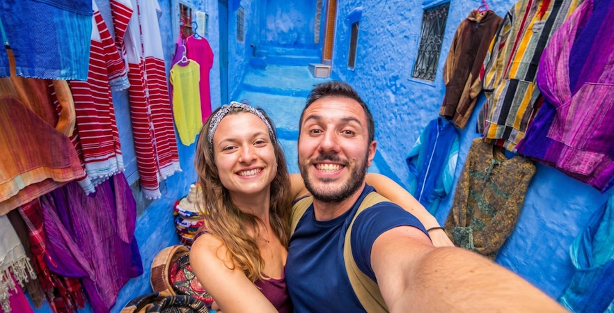 Couple taking a selfie in the vibrant blue streets of Chefchaouen, Morocco.