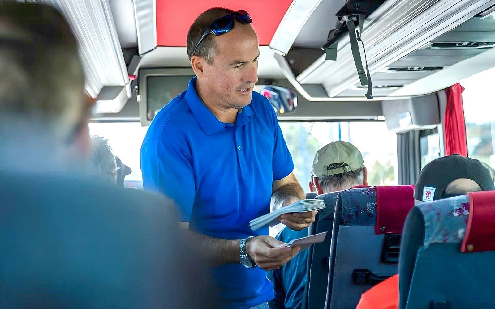 Guide discussing Pompeii ruins with tourists inside a private coach en route to Amalfi Coast.