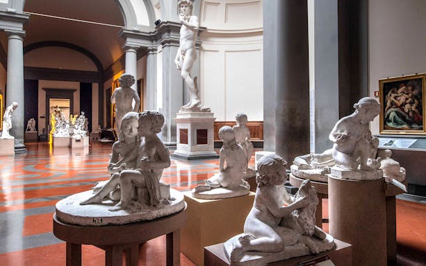Sculptures in Accademia Gallery, Florence, with Michelangelo's David in the background.