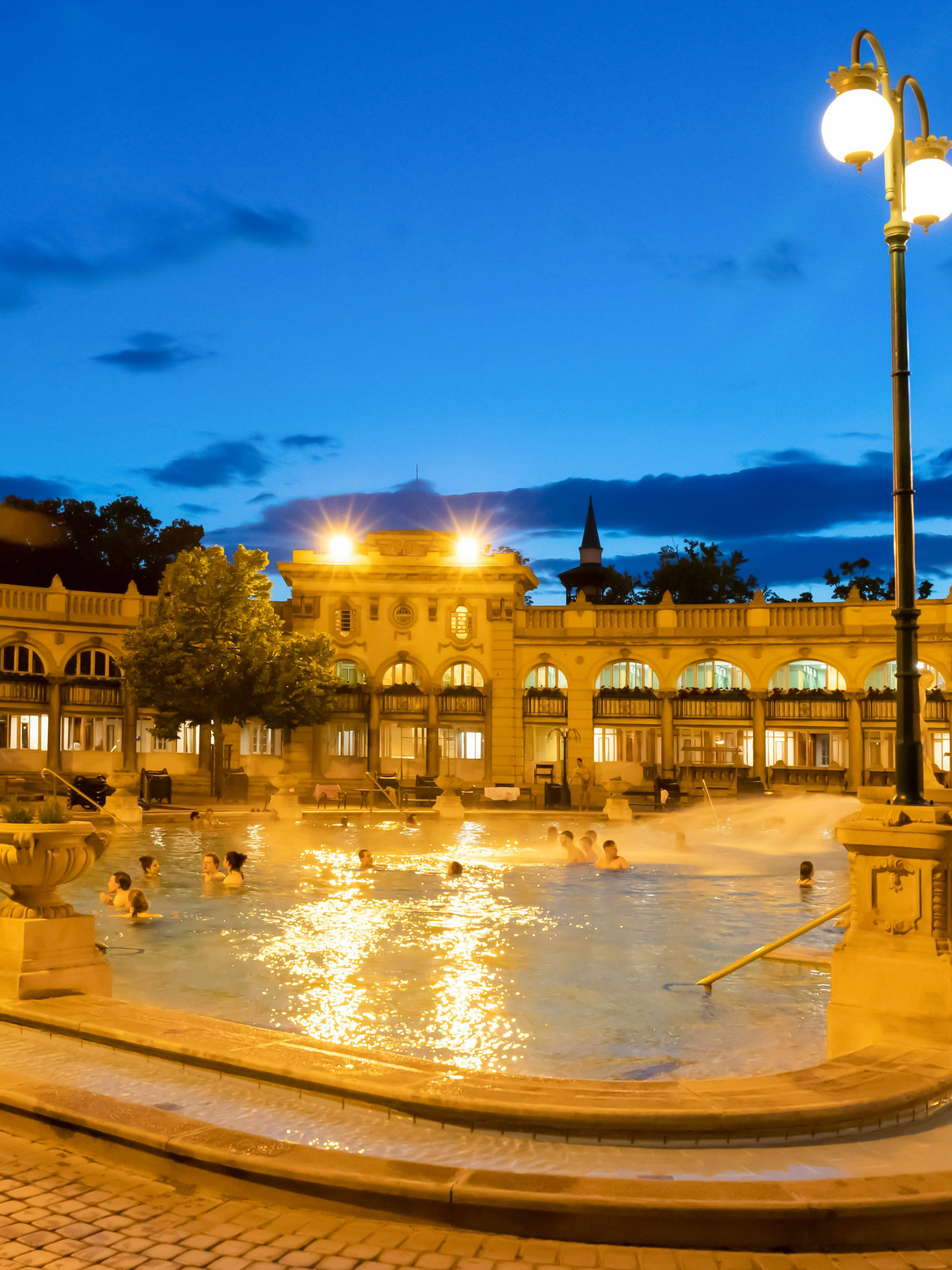 Outdoor pools at Szechenyi Thermal Bath in Budapest during evening.