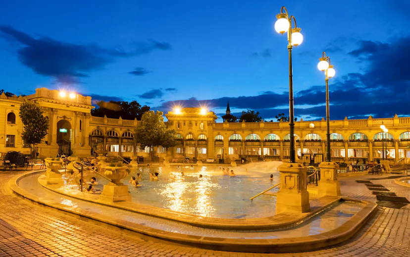 Outdoor pools at Szechenyi Thermal Bath in Budapest during evening.