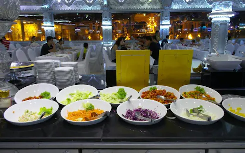 Buffet spread at Phuket FantaSea Show with salads and dining area in background.