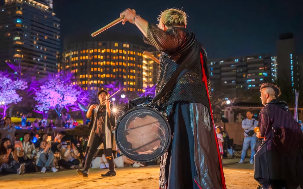 Drummers performing at night during the Ōgimachi Sakura Festival with illuminated cherry blossoms.