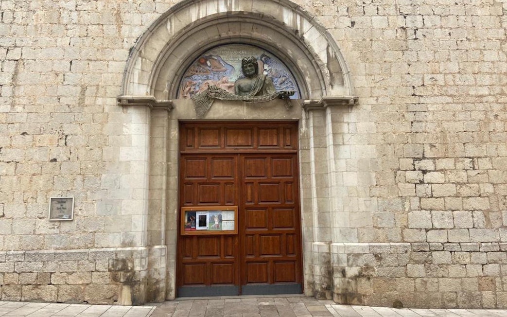 Entrance to the Church of Sant Pere in Figueres, Catalonia, Spain, featuring a wooden door and stone arch.