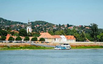 Cruise boat on the Danube River with Szentendre town and church in the background.