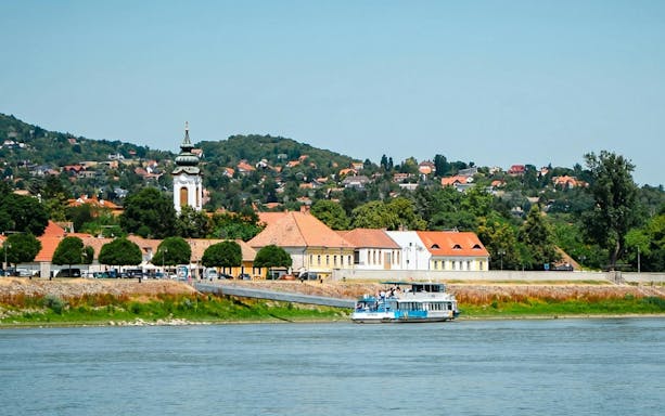 Cruise boat on the Danube River with Szentendre town and church in the background.