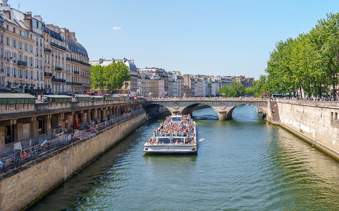 Seine River cruise boat passing under a bridge in Paris, France.