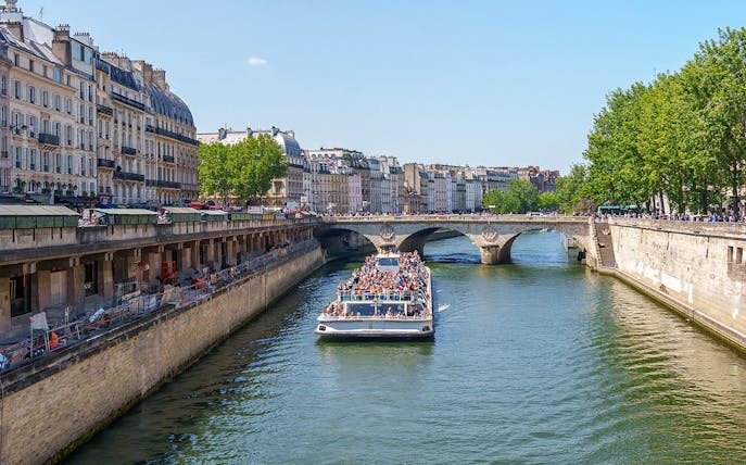 Seine River cruise boat passing under a bridge in Paris, France.