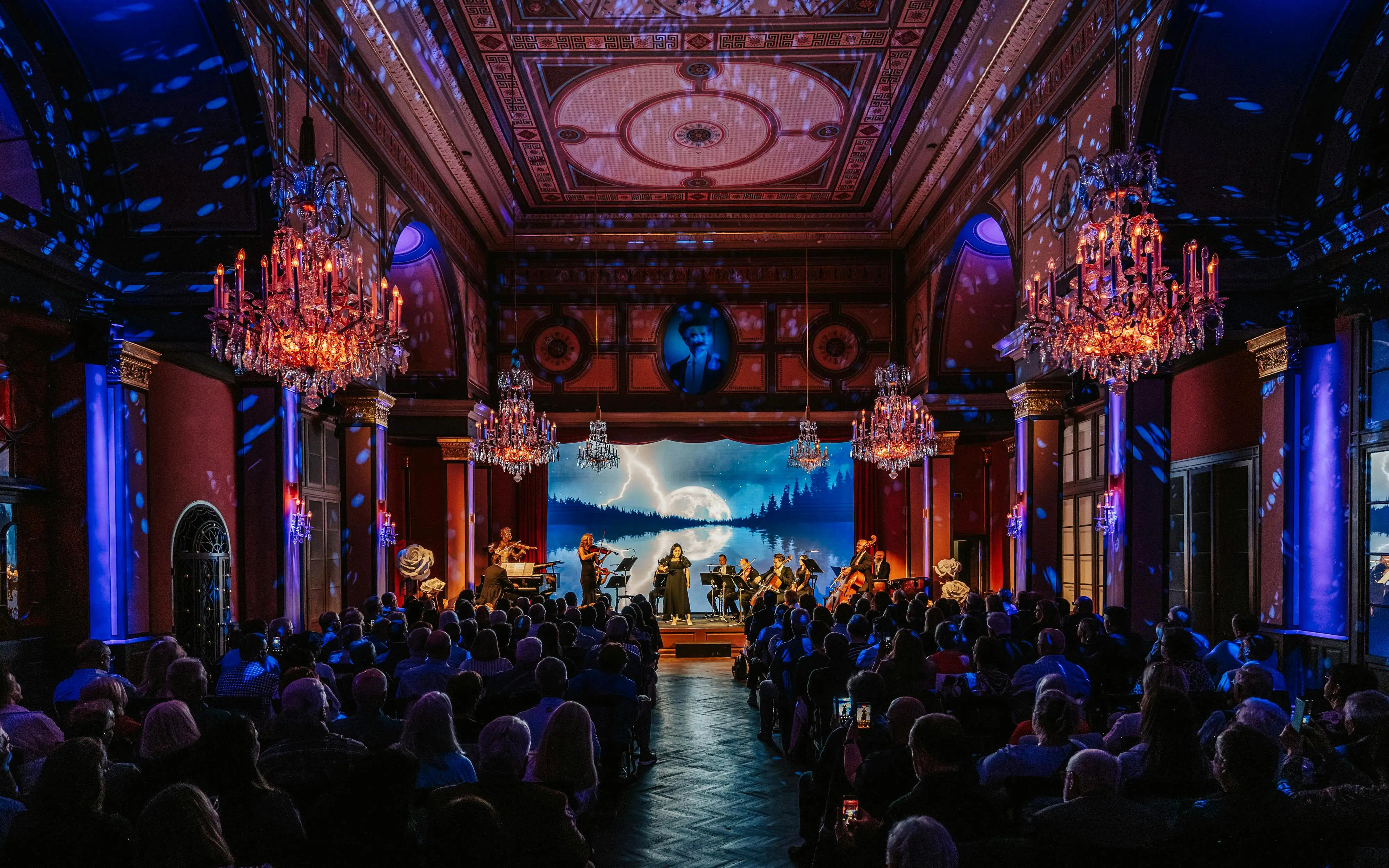 Classical concert in Vienna with musicians performing on stage under chandeliers.