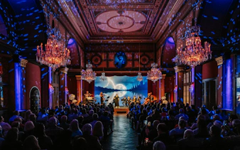 Classical concert in Vienna with musicians performing on stage under chandeliers.