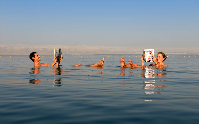 Couple reading while floating in the Dead Sea, Jordan.