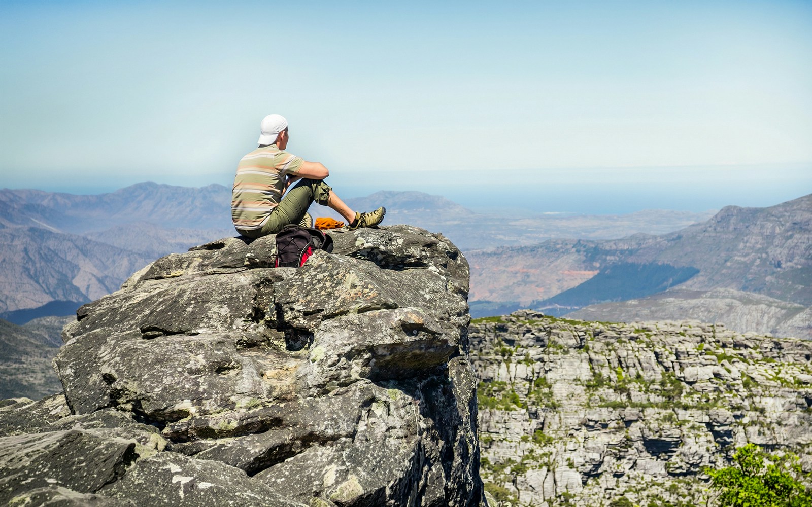 Man sitting on rocks, viewing landscape from Table Mountain, Cape Town.