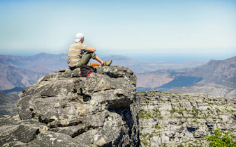 Man sitting on rocks, viewing landscape from Table Mountain, Cape Town.