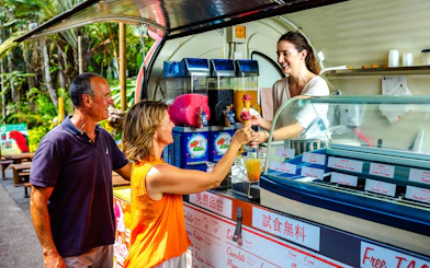 Tourists enjoying ice cream at a Kuranda market stall during the Scenic Train and Skyrail Kuranda Tour.