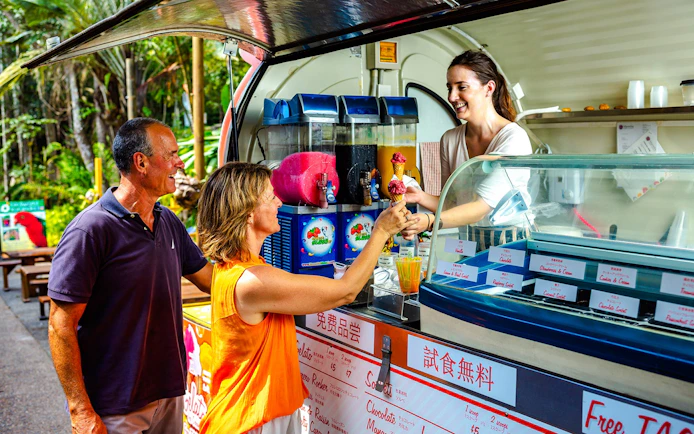 Tourists enjoying ice cream at a Kuranda market stall during the Scenic Train and Skyrail Kuranda Tour.