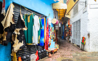Colorful market street in Tangier with traditional garments and crafts.