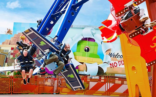 Visitors enjoying a ride at LEGOLAND® Billund with colorful LEGO-themed backdrop.