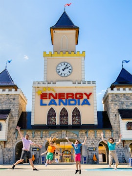 Visitors jumping in front of Energylandia Amusement Park entrance, Krakow.