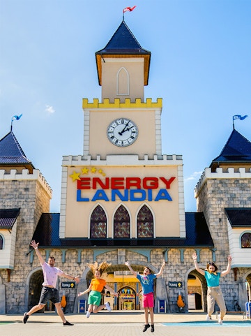Visitors jumping in front of Energylandia Amusement Park entrance, Krakow.