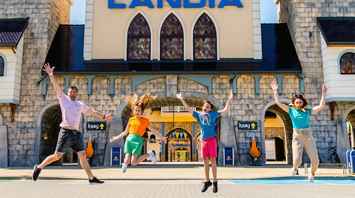 Visitors jumping in front of Energylandia Amusement Park entrance, Krakow.