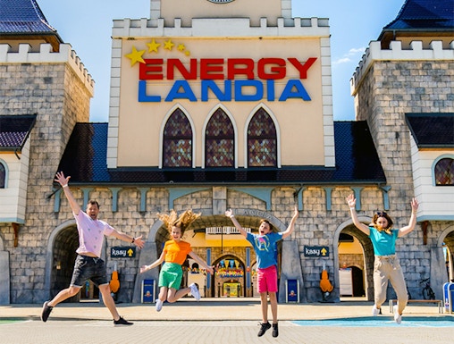 Visitors jumping in front of Energylandia Amusement Park entrance, Krakow.