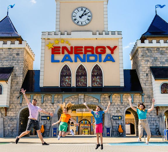 Visitors jumping in front of Energylandia Amusement Park entrance, Krakow.