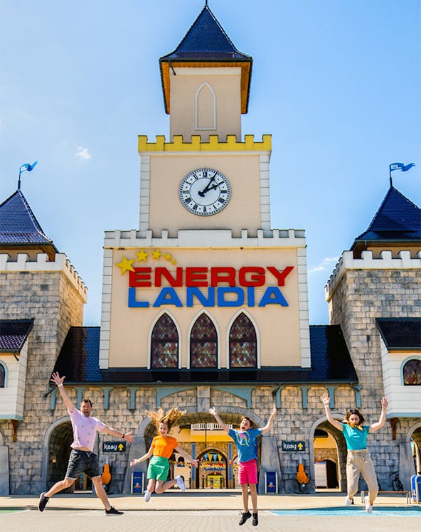 Visitors jumping in front of Energylandia Amusement Park entrance, Krakow.