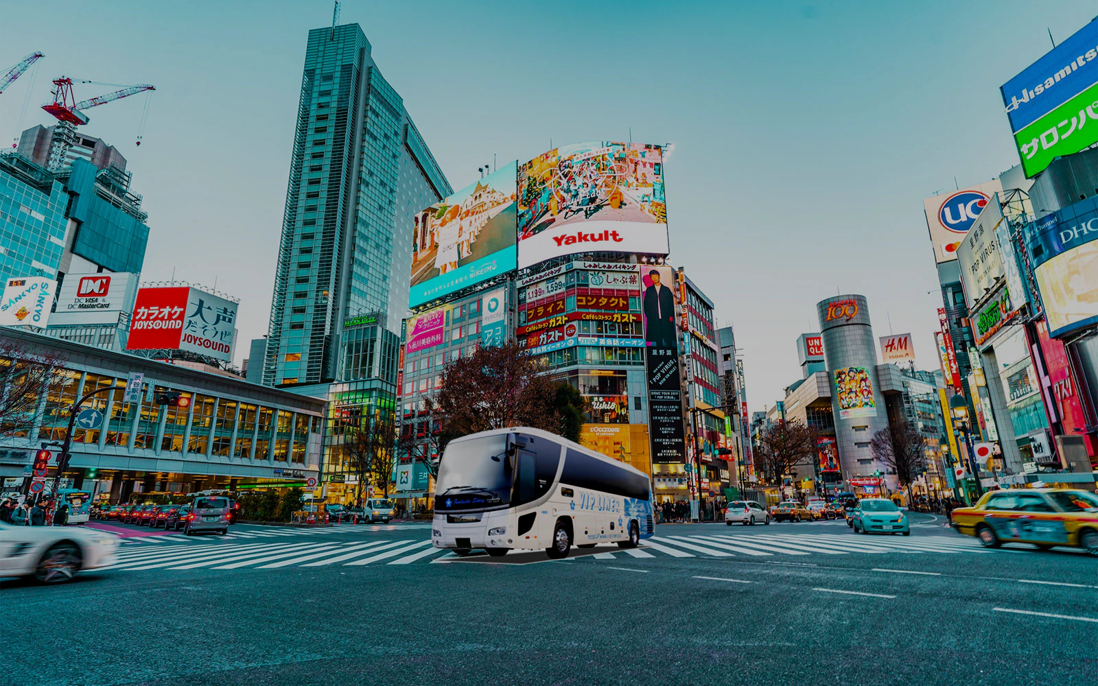 Overnight highway bus in Shibuya, Tokyo, with cityscape and billboards.