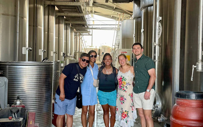 Group enjoying a guided wine tour inside a Tuscan winery cellar.