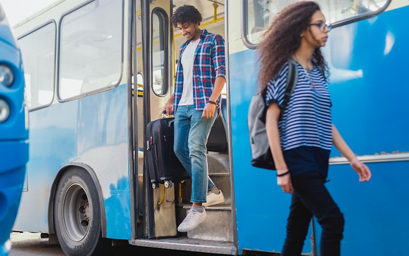 Man exiting bus with luggage in hand.