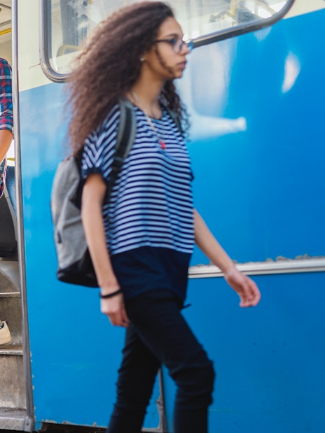 Man exiting bus with luggage in hand.
