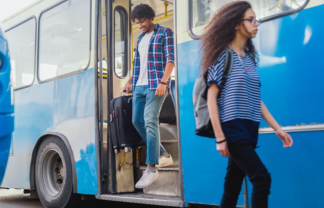 Man getting off the bus with luggage in his hand
