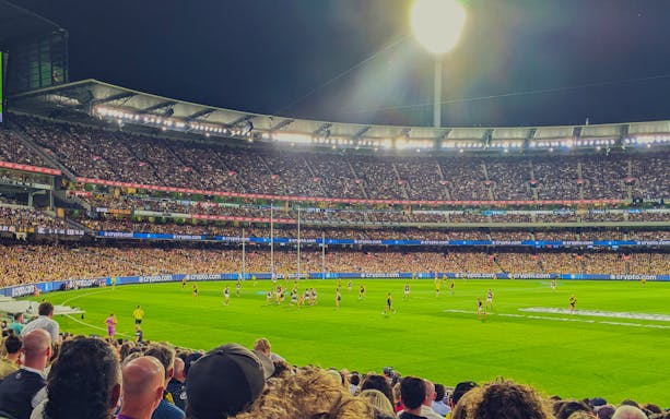 Australian Rules football match at Melbourne Cricket Ground, crowded stands.