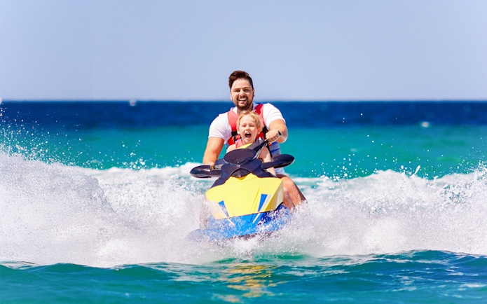 Father and son riding a jetski on Langkawi island hopping tour.